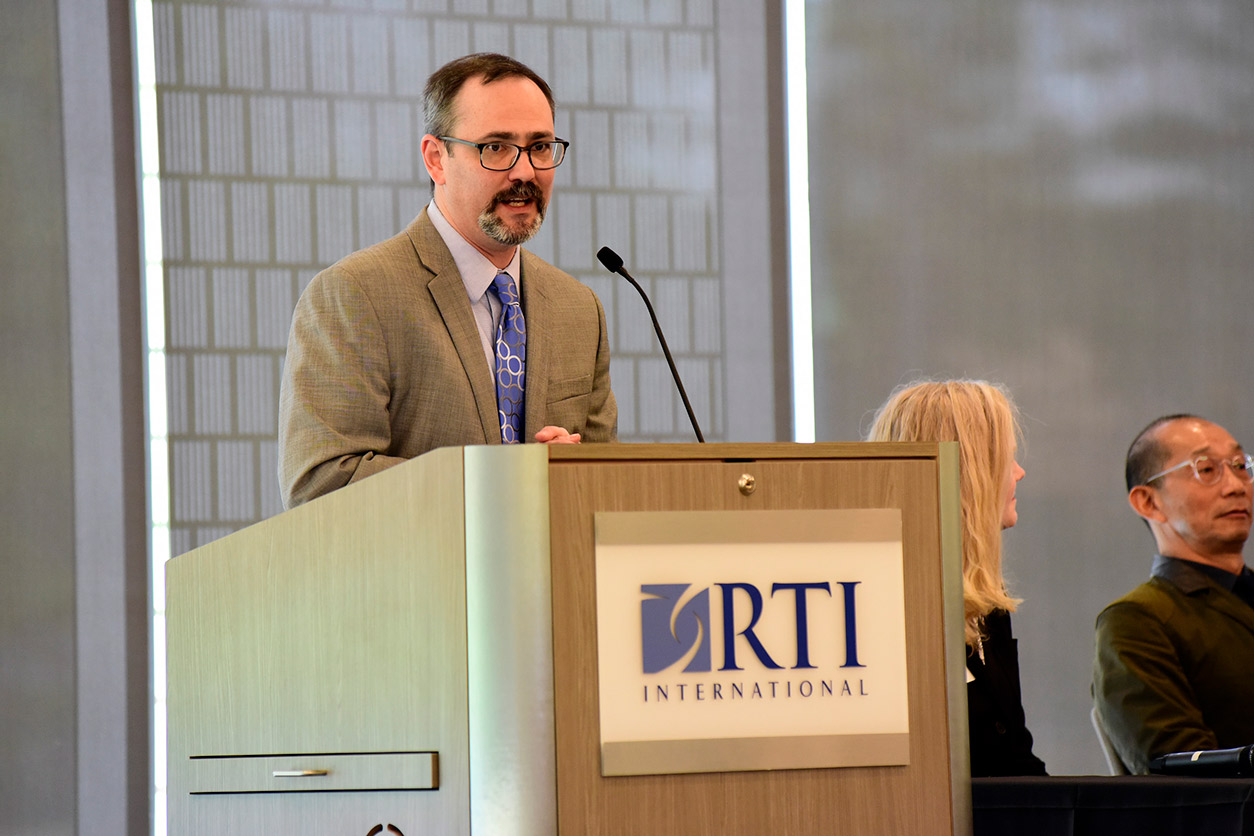 Jacob Traverse stands at podium with RTI International sign