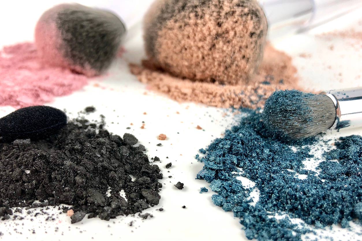 broken pieces of powders, eye shadows, and blush with coated brushes
