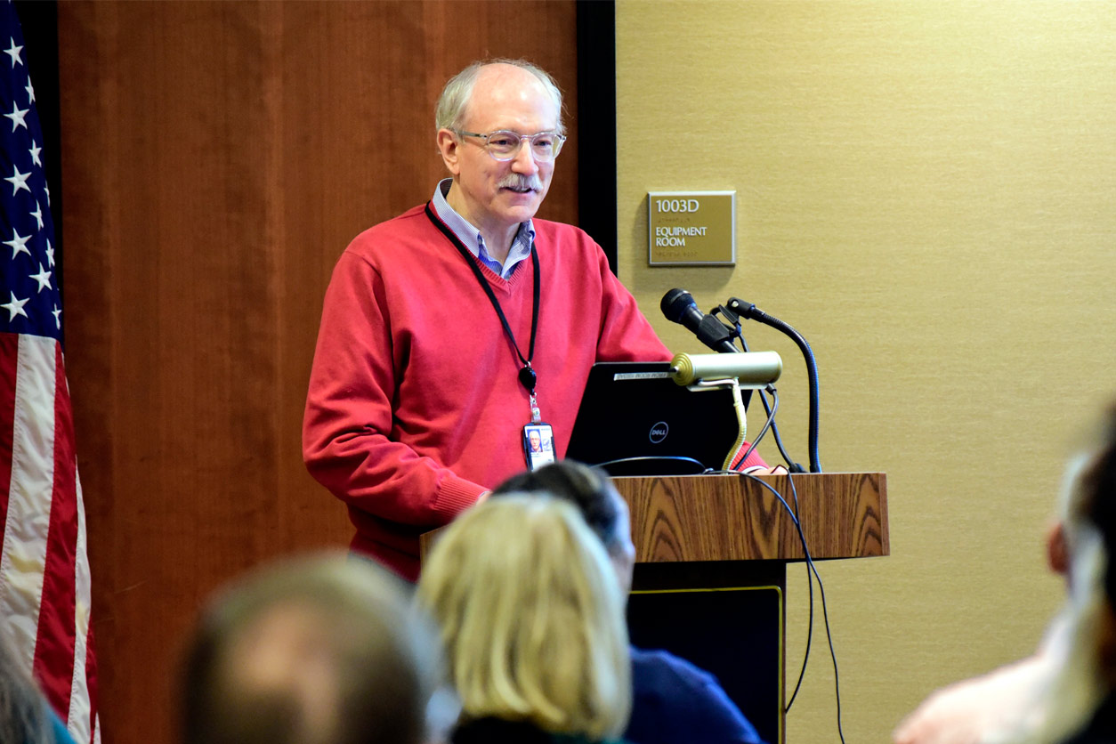 Rick Woychik, Ph.D. smiles at the audience from the podium