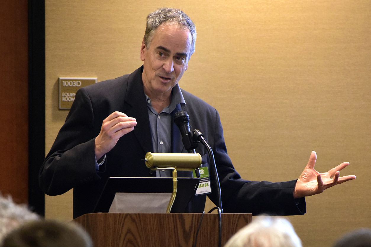 Julian Schroeder, Ph.D. animatedly speaks to audience from podium