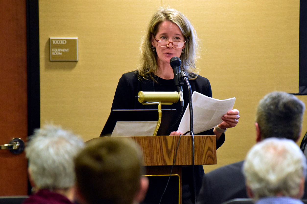Michelle Heacock, Ph.D. holds papers and speaks to audience from podium