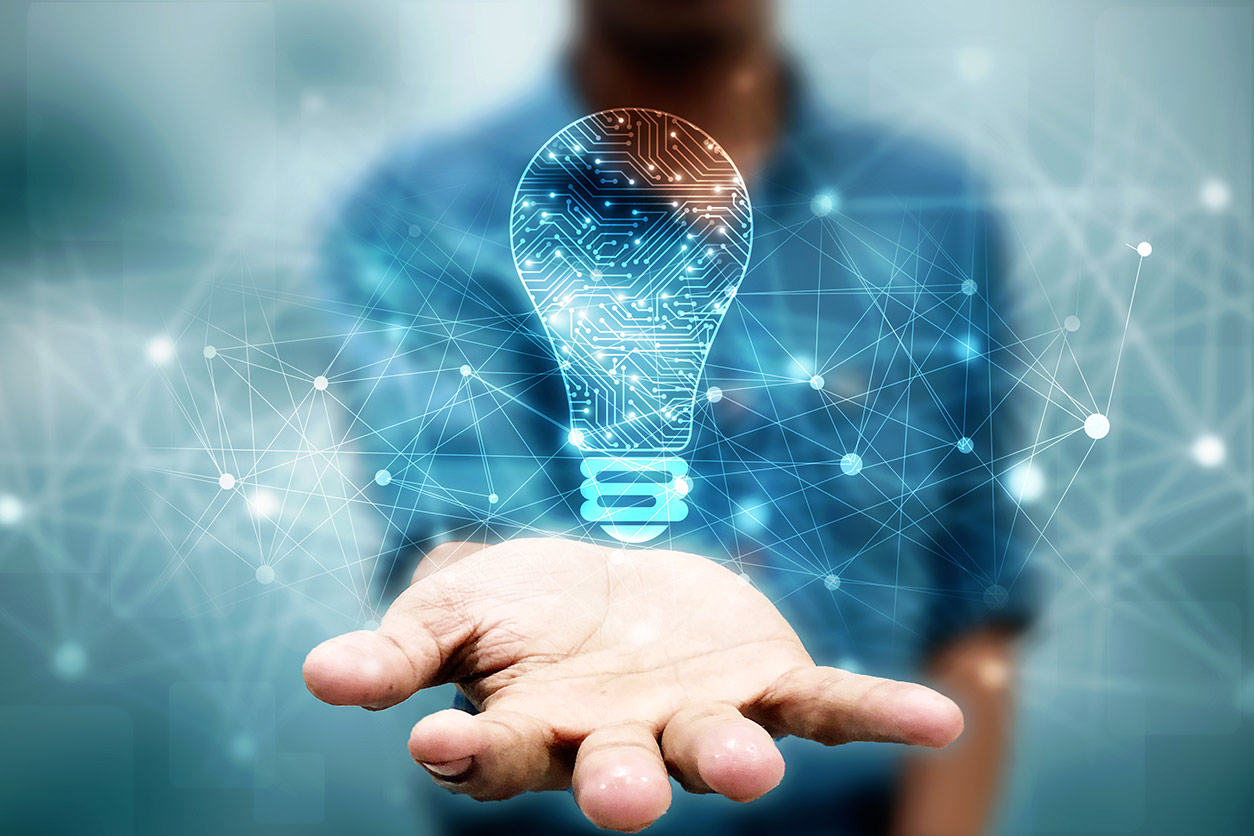 hand in foreground with light bulb holding innovative technology floating above