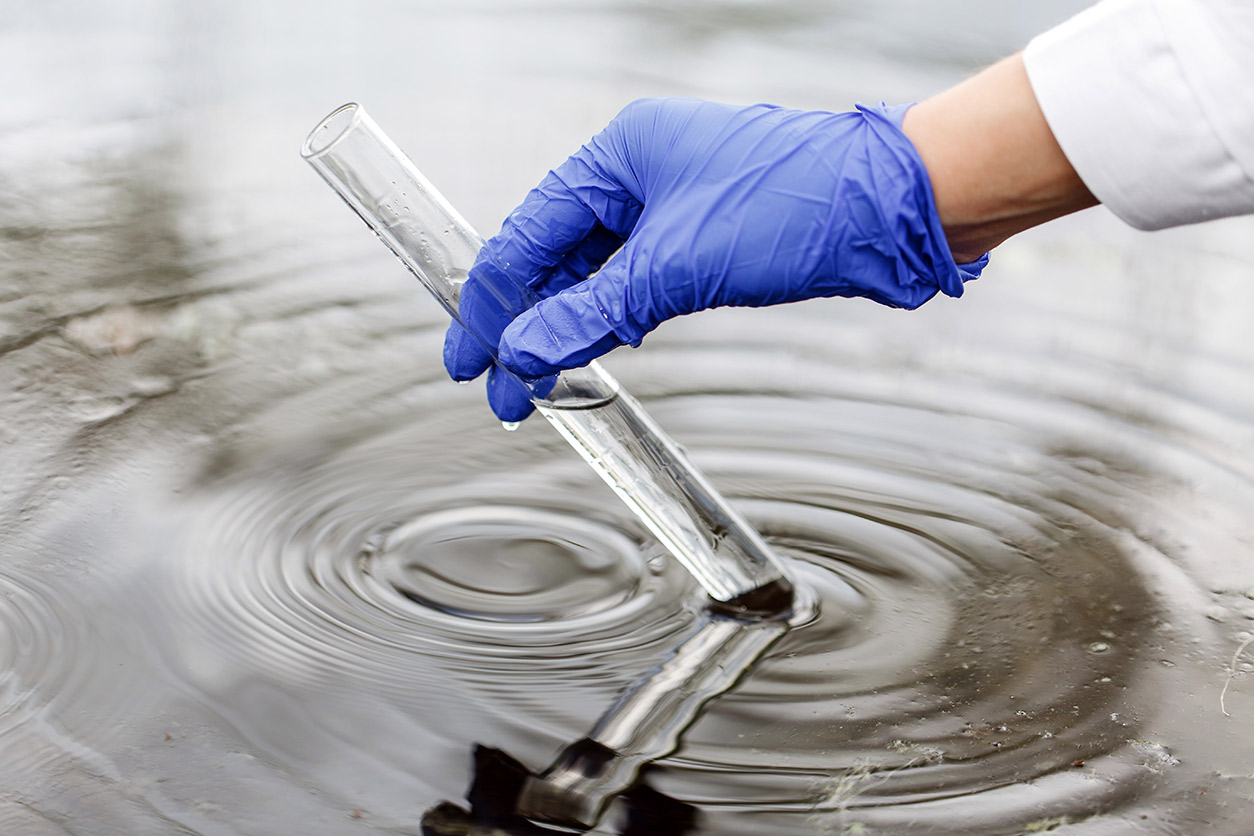 gloved hand holds water in a test tube