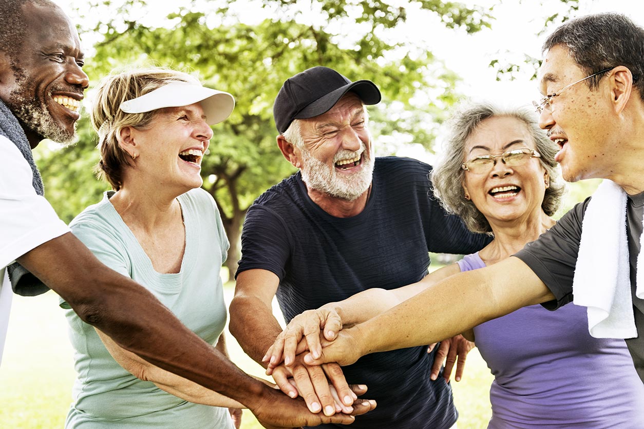 diverse group of older people putting their hands together