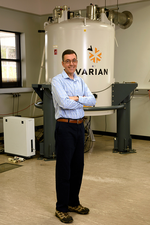 Mueller stands next to the Nuclear Magnetic Resonance Spectrometer