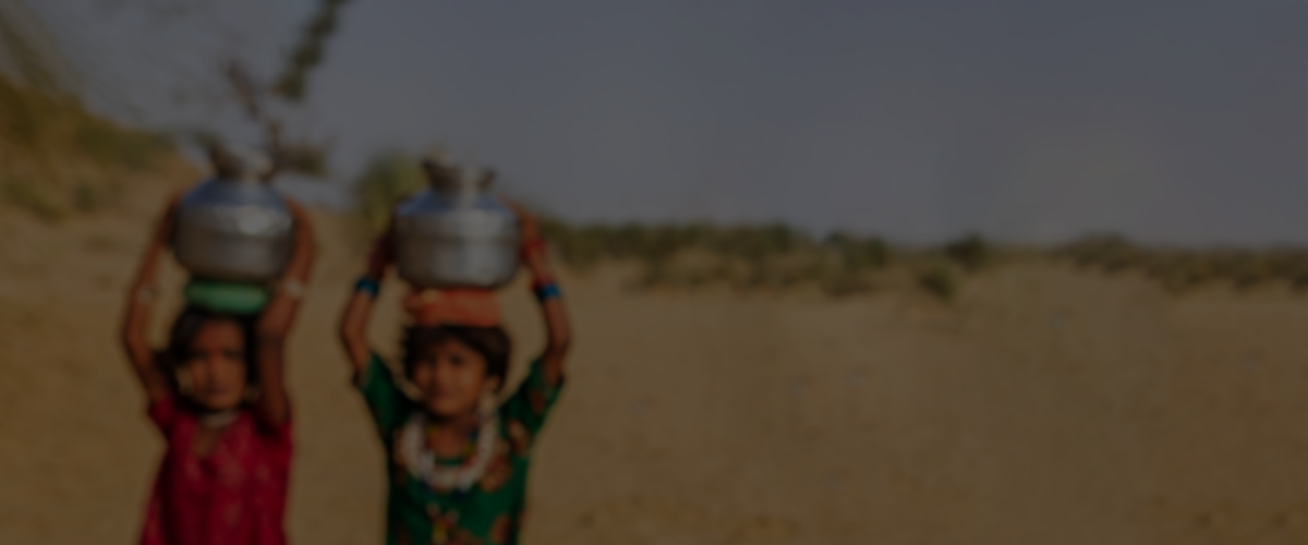 A young girl carries a pot on her head